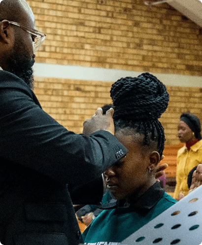 Picture of a man on his knees on the floor praying in a crowd of people